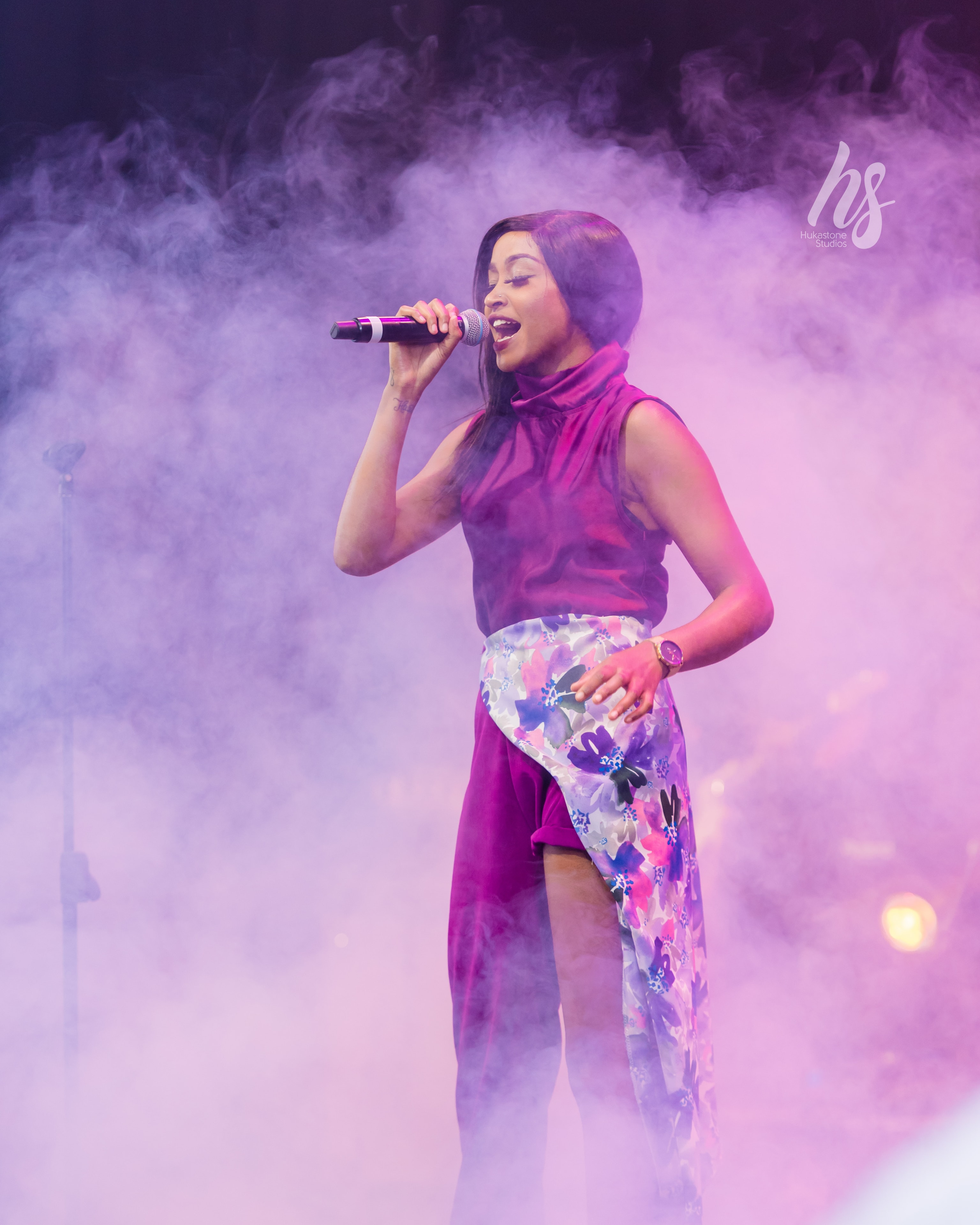 Singer performing on stage with dramatic purple atmospheric lighting