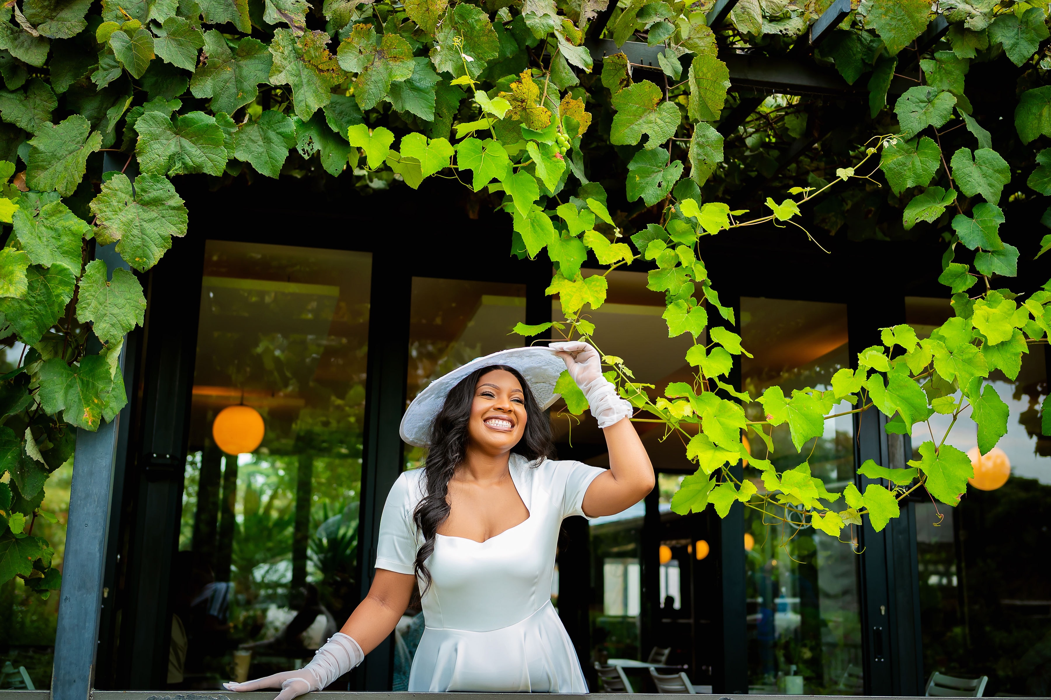 Bride standing beneath grapevines with her bouquet