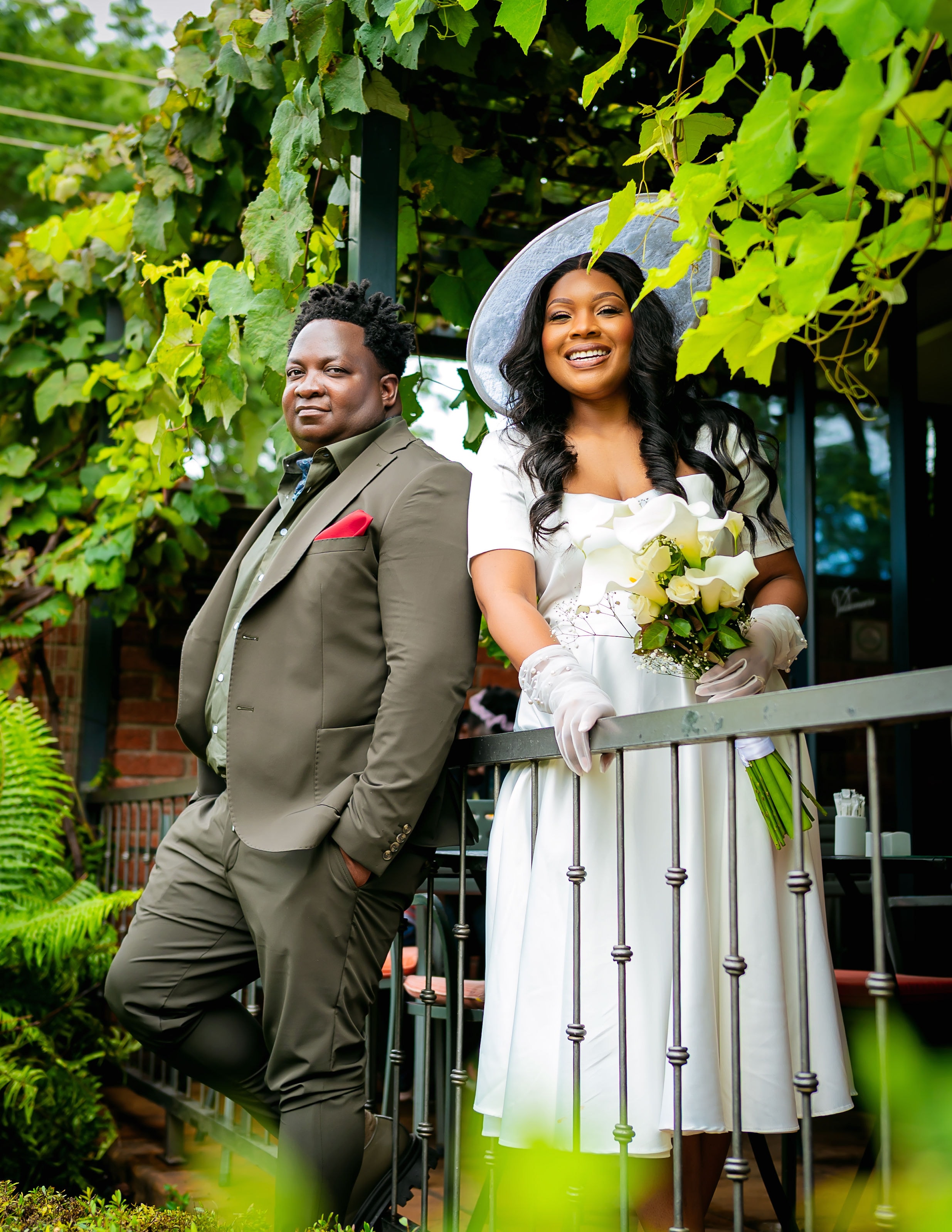Bride and groom posing beneath lush grapevines
